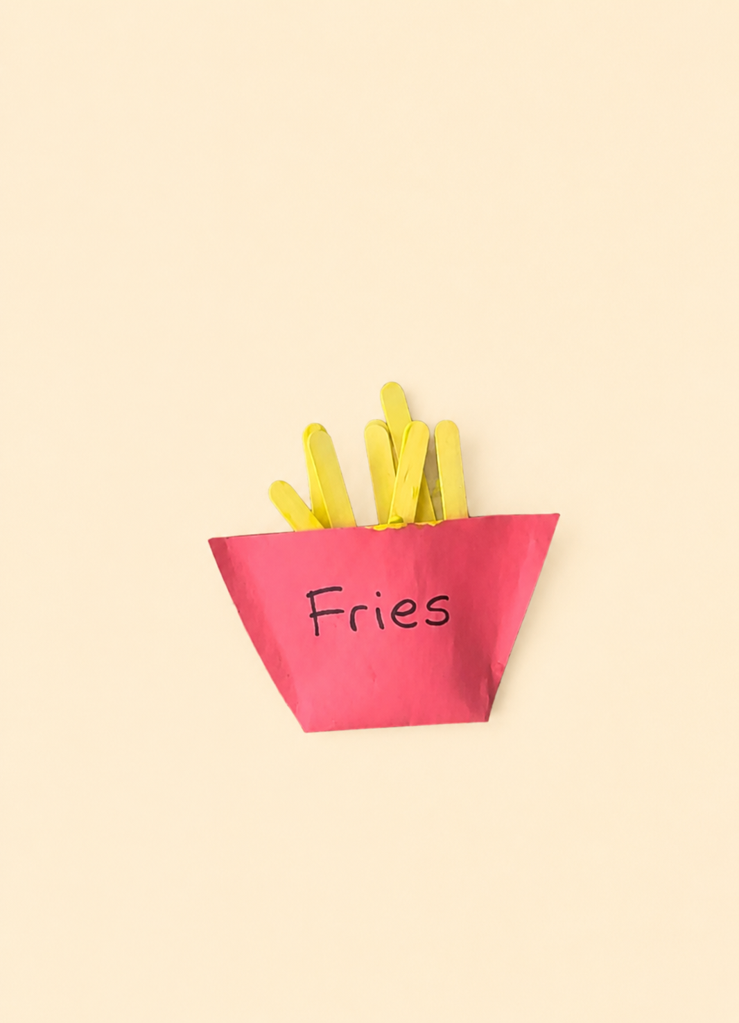 Preschool popsicle stick fries craft with yellow craft stick fries inside a red paper box