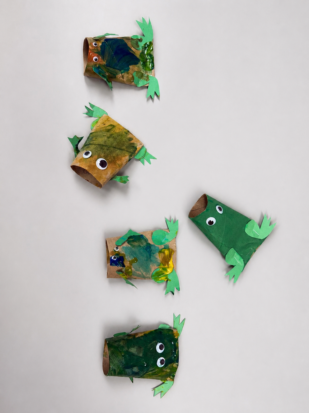 Preschool paper roll frog crafts painted green with paper legs and wiggly eyes